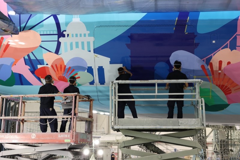 Painters stand on lifts as they work on the details of the special livery.