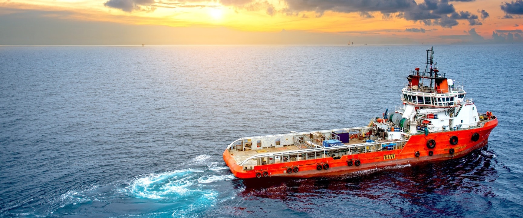 Coastal support vessel navigating open waters at sunset, representing reliable coatings for coastal and inland vessels.