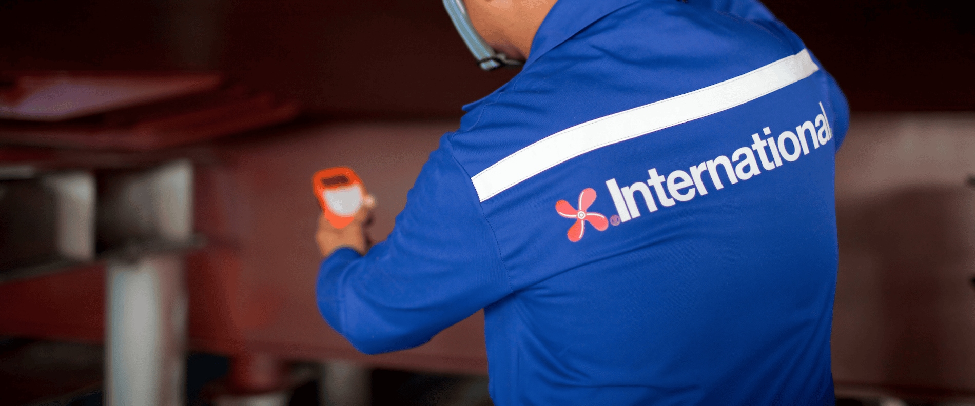 International Marine Coatings technical service team in blue protective gear and helmets working at a shipyard.