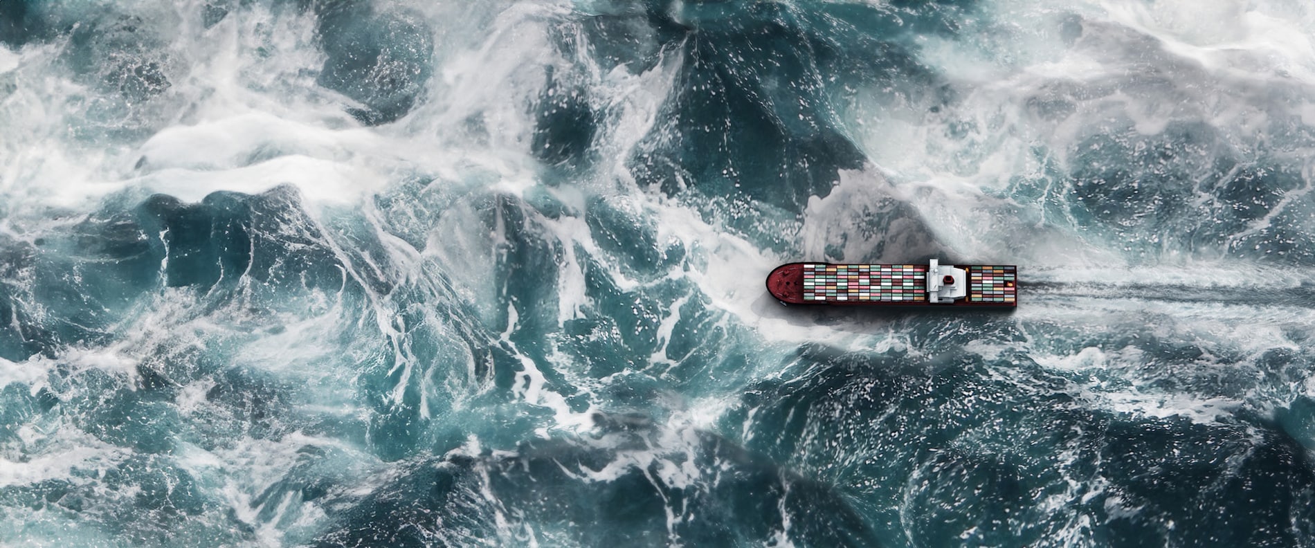 Cargo ship with containers navigating rough ocean waves, representing marine coatings for extreme sea conditions.