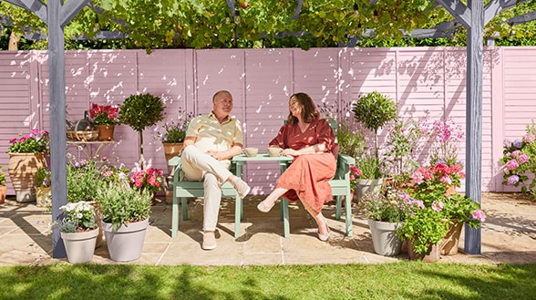 Image of a couple enjoying lunch in their garden painted with Cuprinol