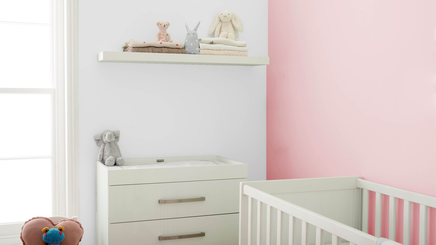 Une commode et des étagères à fixation invisible blanches sont la solution idéale pour ranger les couches et autres articles de puériculture.