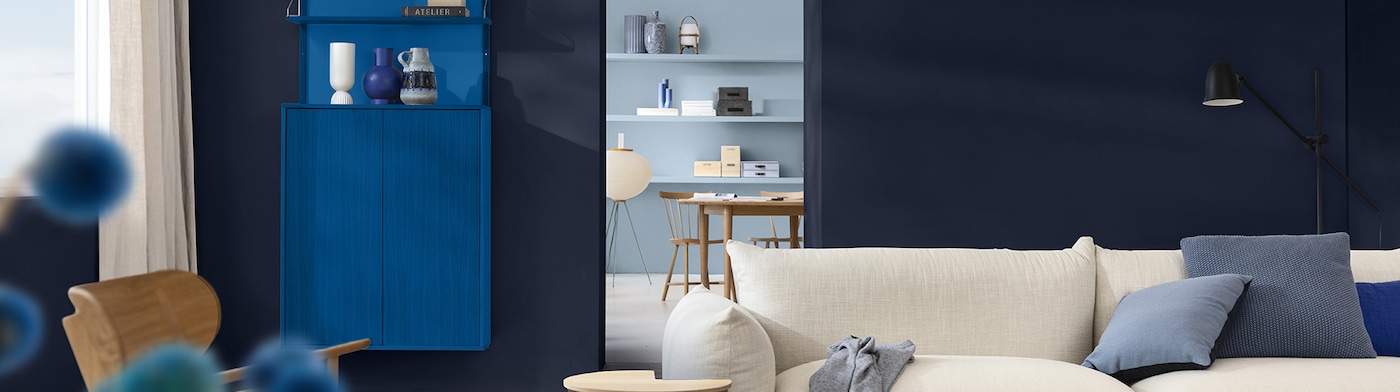 Living room with blue-painted walls, white sofa and wooden cupboard