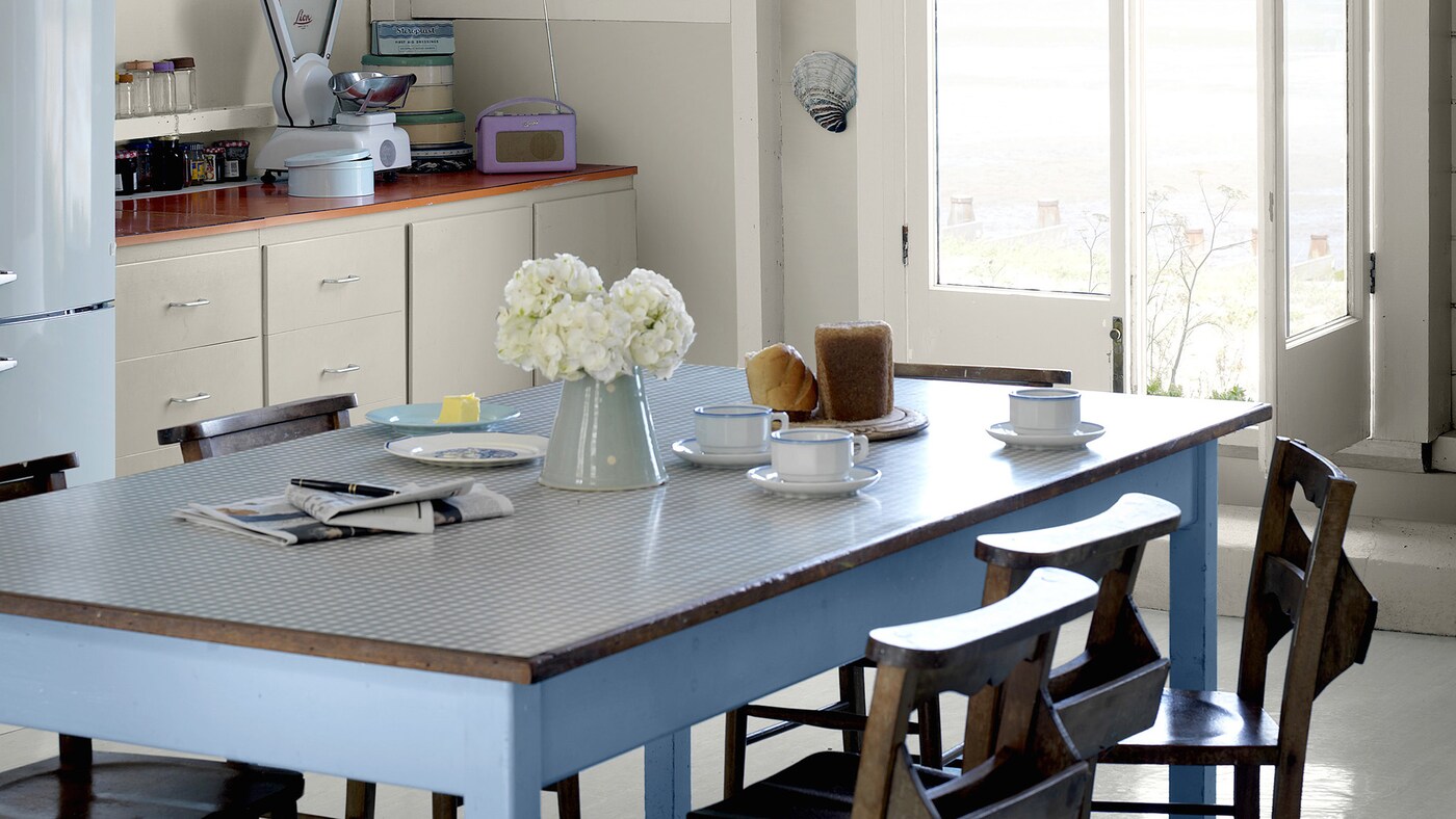 English country style kitchen decorated in cool neutrals with a blue dining table