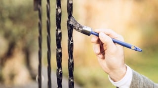Ein Geländer im Außenbereich wir mit einem Pinsel gestrichen
