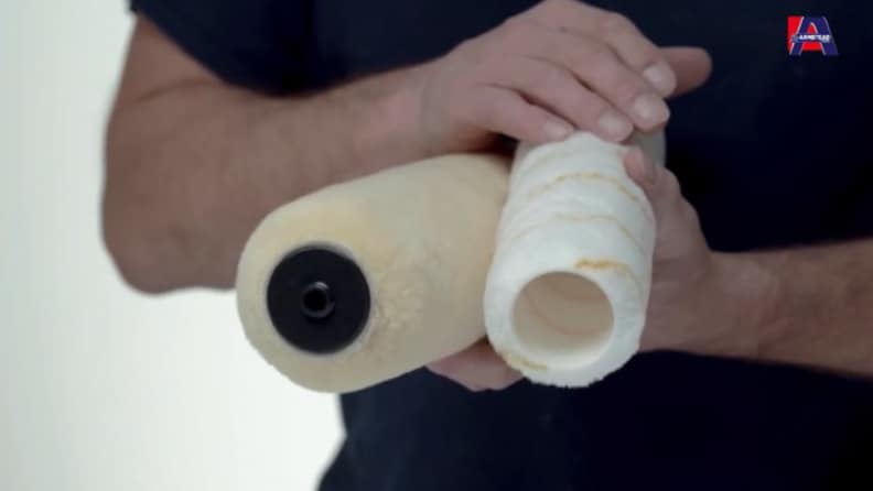 Hands demonstrating two white paint roller covers showing their different core sizes - one with a black core and one with a beige core - with the Armstead logo in the corner.