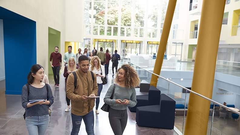 Studerende går gennem en indgang med farverige nicher og okkerfarvede søjler