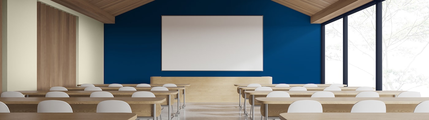 Skrivebord og hvide stole mod en blå væg