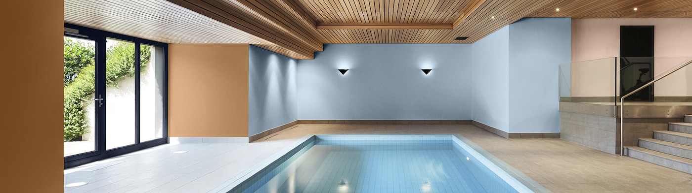 Hotel swimmingpool med naturligt træloft og blå væg