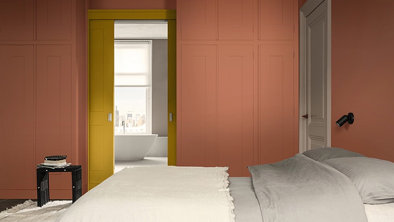 Et varmt og hyggeligt hotelværelse malet i terrakottarød og gul