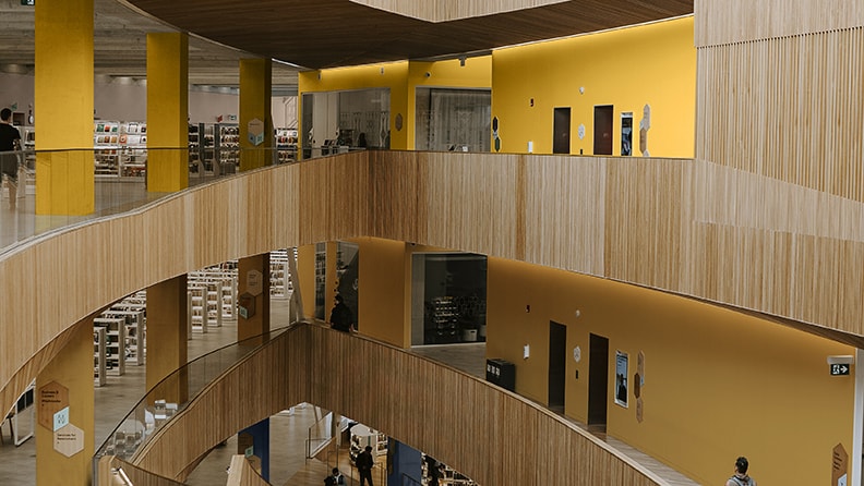 Et moderne bibliotek i flere niveauer. Gulmalede vægge skiller sig ud fra træpanelerne