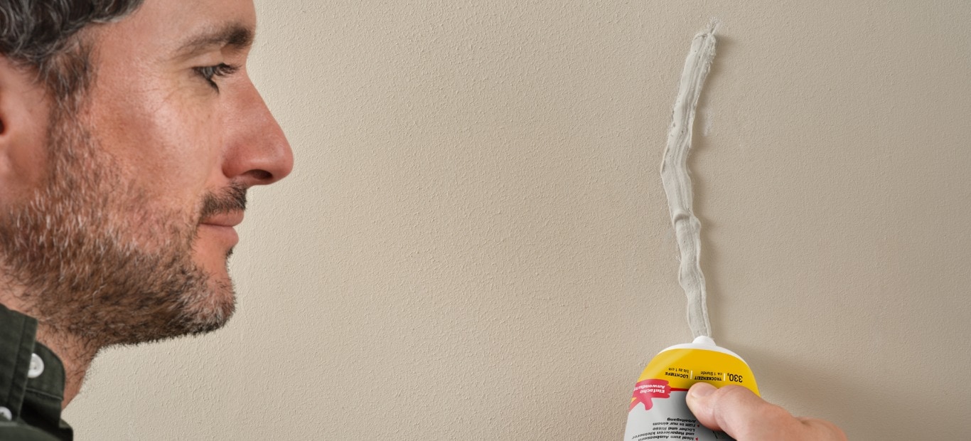Ein Mann füllt einen Riss in einer Wand mit dem Innen Reparatur Moltofill von Molto