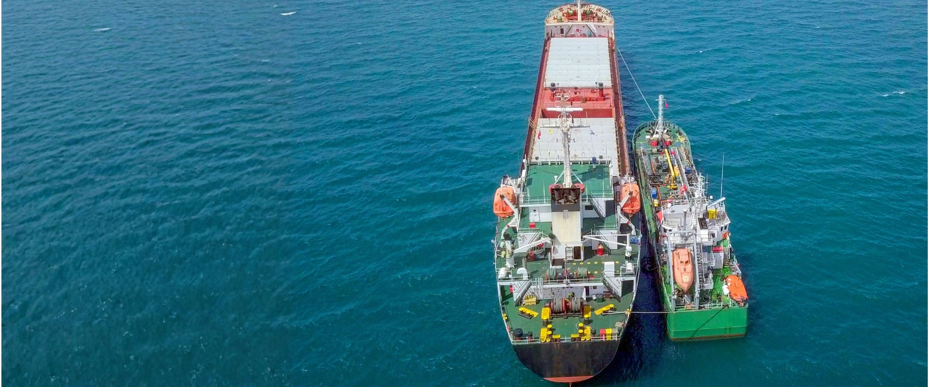 Aerial view of two vessels alongside each other at sea during ship-to-ship bunkering.