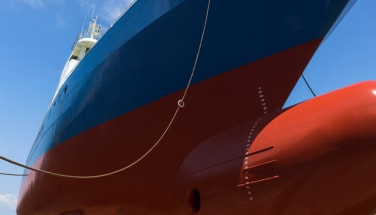 Large vessel hull with smooth coated underwater area viewed from dockside