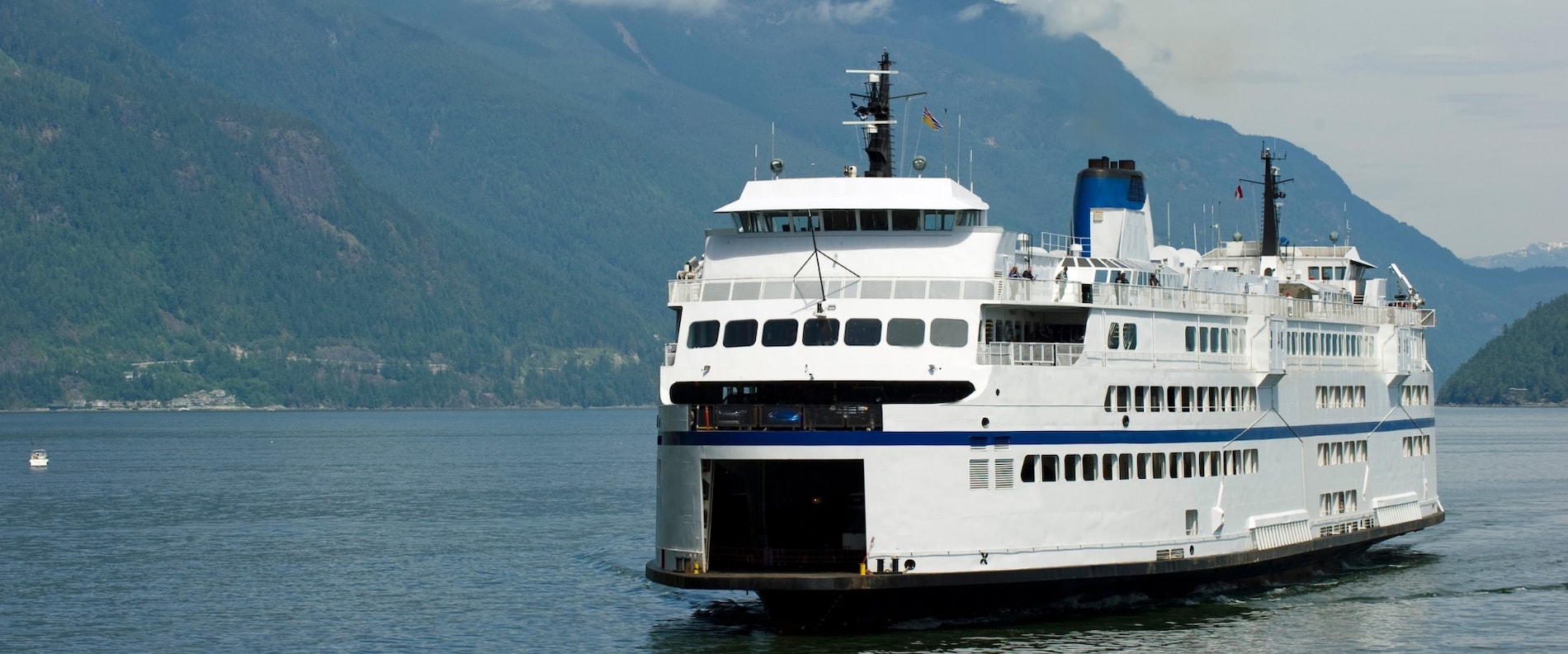 Passenger ferry sailing through calm waters with mountains in the background.