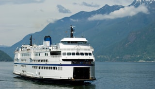 Passenger ferry sailing through calm waters with mountains in the background.