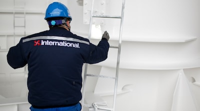International worker inspecting protective coatings inside a ship.