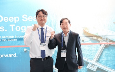 Group photo of International Marine Coatings representatives at Kormarine 2025, standing in front of campaign graphics.