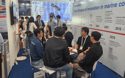 Visitors engaging with International Marine Coatings representatives at the exhibition booth.