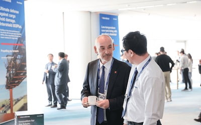 Delegates networking during Kormarine 2025, with International Marine Coatings campaign displays in the background.