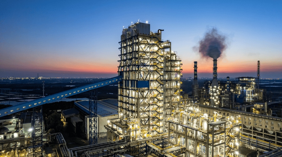Large onshore industrial plant at sunset showing steel structures and refinery equipment.