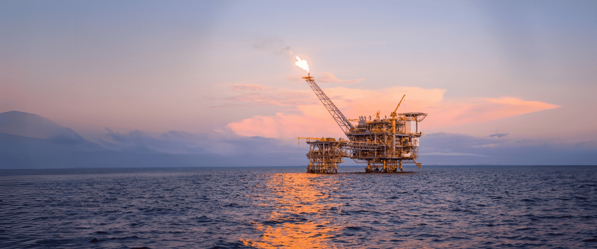 Offshore oil and gas platform at sunset, highlighting the need for passive fire protection solutions like Chartek ONE.