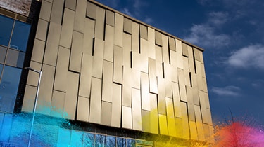 Modern building facade with golden anodic powder coatings panels under blue sky