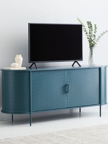 Mueble de metal perforado de color azul para televisión con una pantalla plana, un jarrón y una planta encima.
