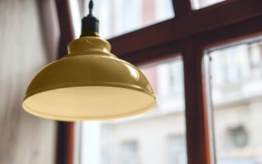 Close-up of golden powder-coated lamp near window