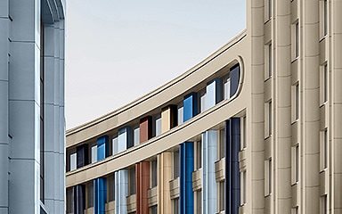 Curved modern building with blue, brown, and beige window frames between tall towers.