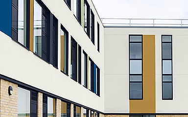Modern residential building with brick base, white facade, and blue, gold, and green panels.
