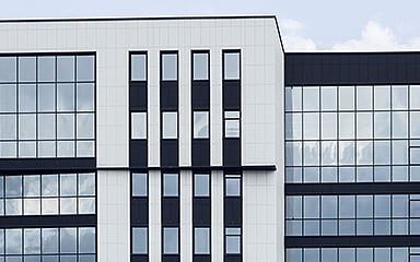 Modern office building with blue window frames, white facade panels, and glass exterior.