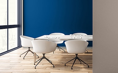 Meeting room with blue accent wall, blue window frames, and white swivel chairs.