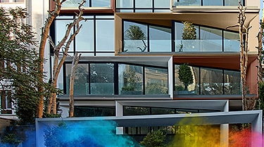 Modern building facade with large blue-framed windows and angled balcony structures.