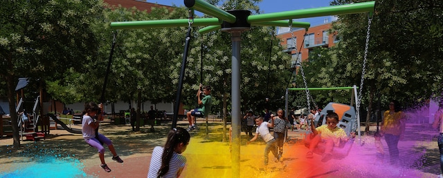 Children playing on a swing and zip line structure in an outdoor playground.