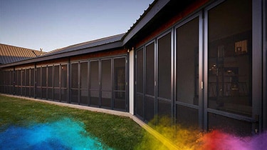 Row of security screen doors and windows on a modern building exterior.