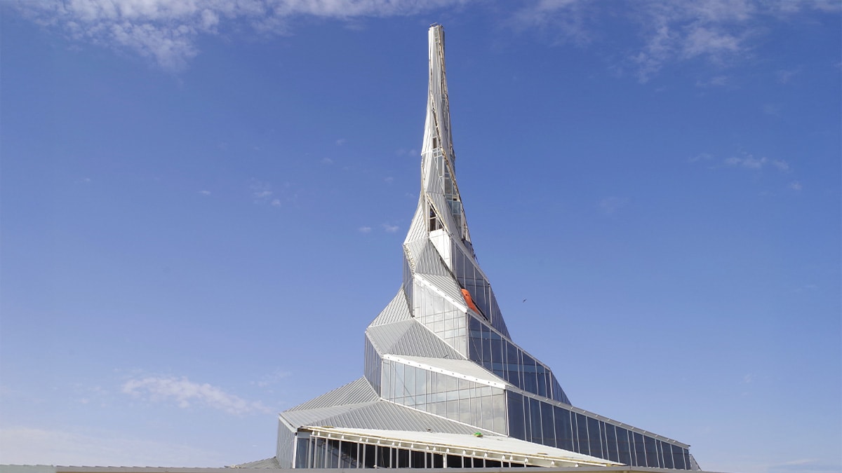 Pointed skyscraper with reflective glass panels under a clear blue sky.