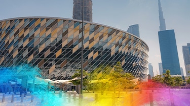 Modern circular arena with diamond façade, set against a city skyline.