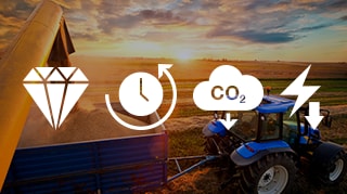 Blue tractor unloading grain at sunset in a field