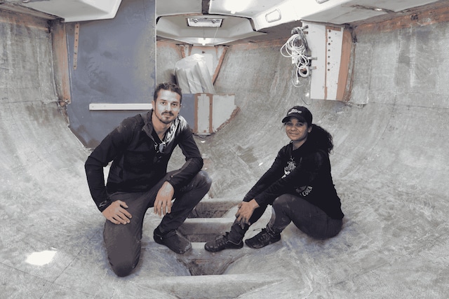 Dan and Kika from Sailing UMA smiling together on the bow of their sailboat