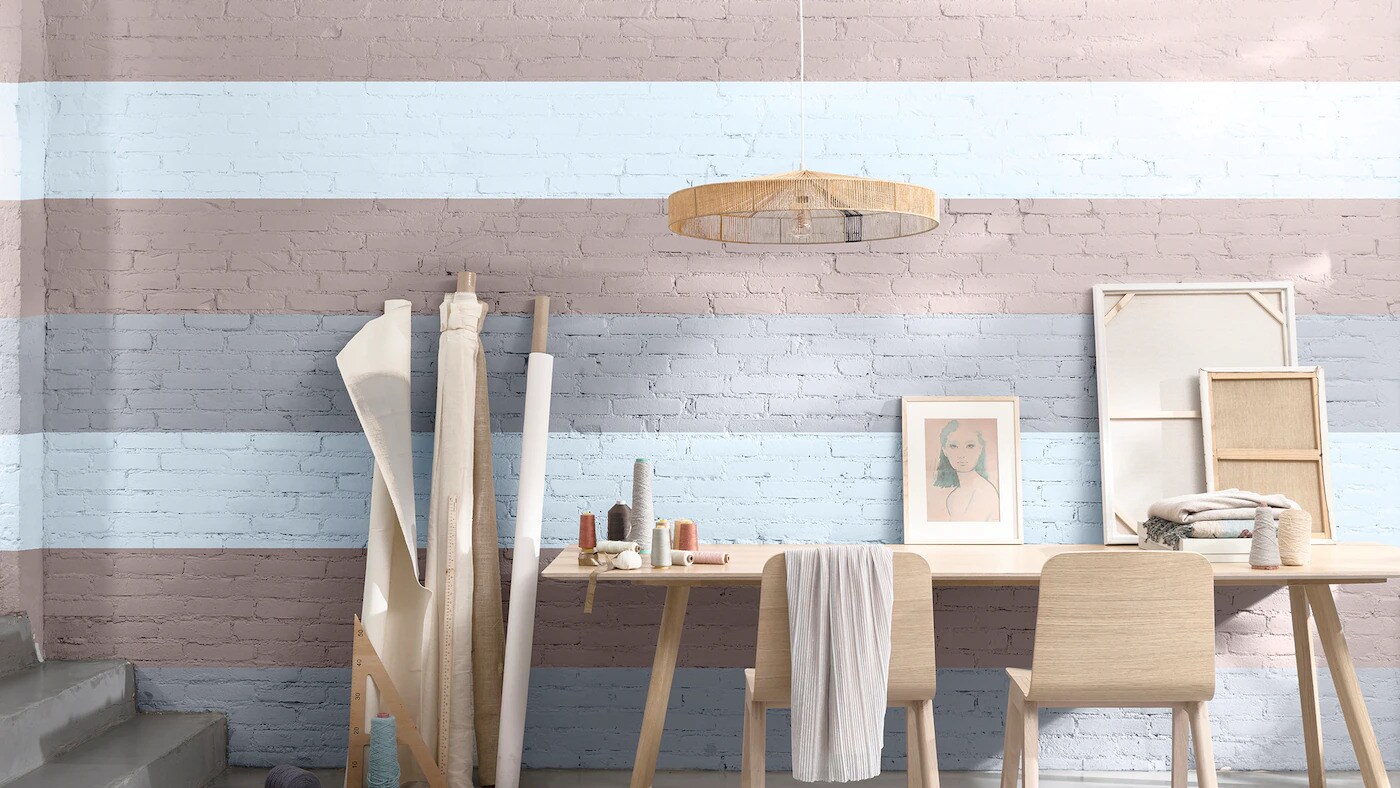 Escritório decorado com listras na parede de tons rosas e lilás combinado com a cor Melodia Suave da Tintas Coral. Uma combinação clara e equilibrada que deixa o ambiente mais agradável.