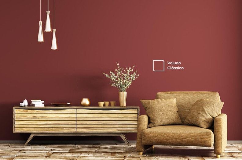 Sala de estar com parede em destaque na cor Veludo Clássico da Tintas Coral. Uma cor vinho que se encaixou perfeitamente no ambiente e combina com a cor marrom do sofá.