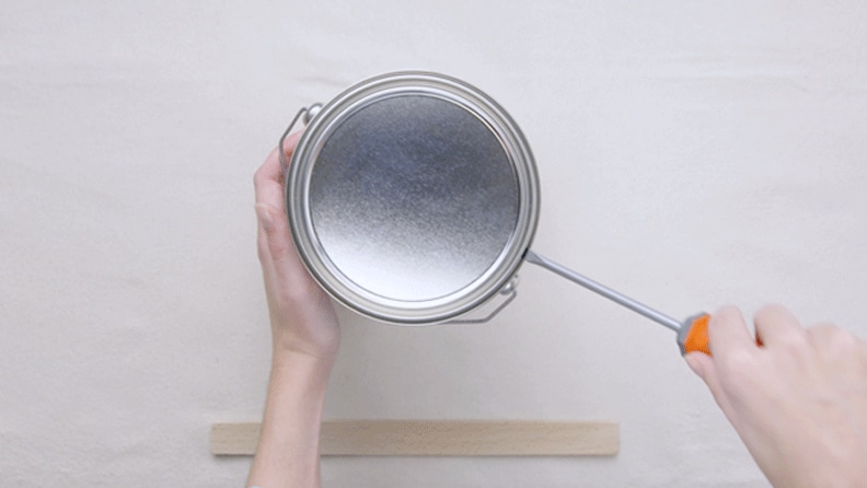 Lata de tinta sendo aberta por uma chave de fenda