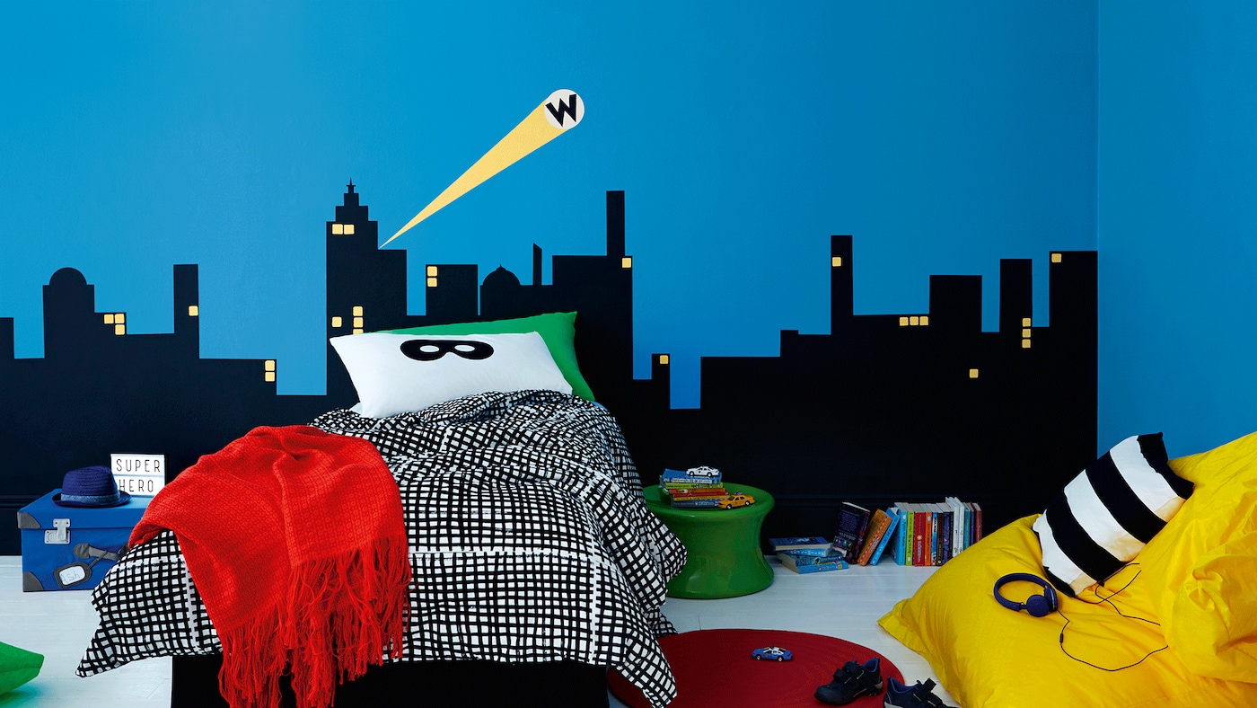 Quarto infantil com paredes decoradas de silhuetas de prédios.