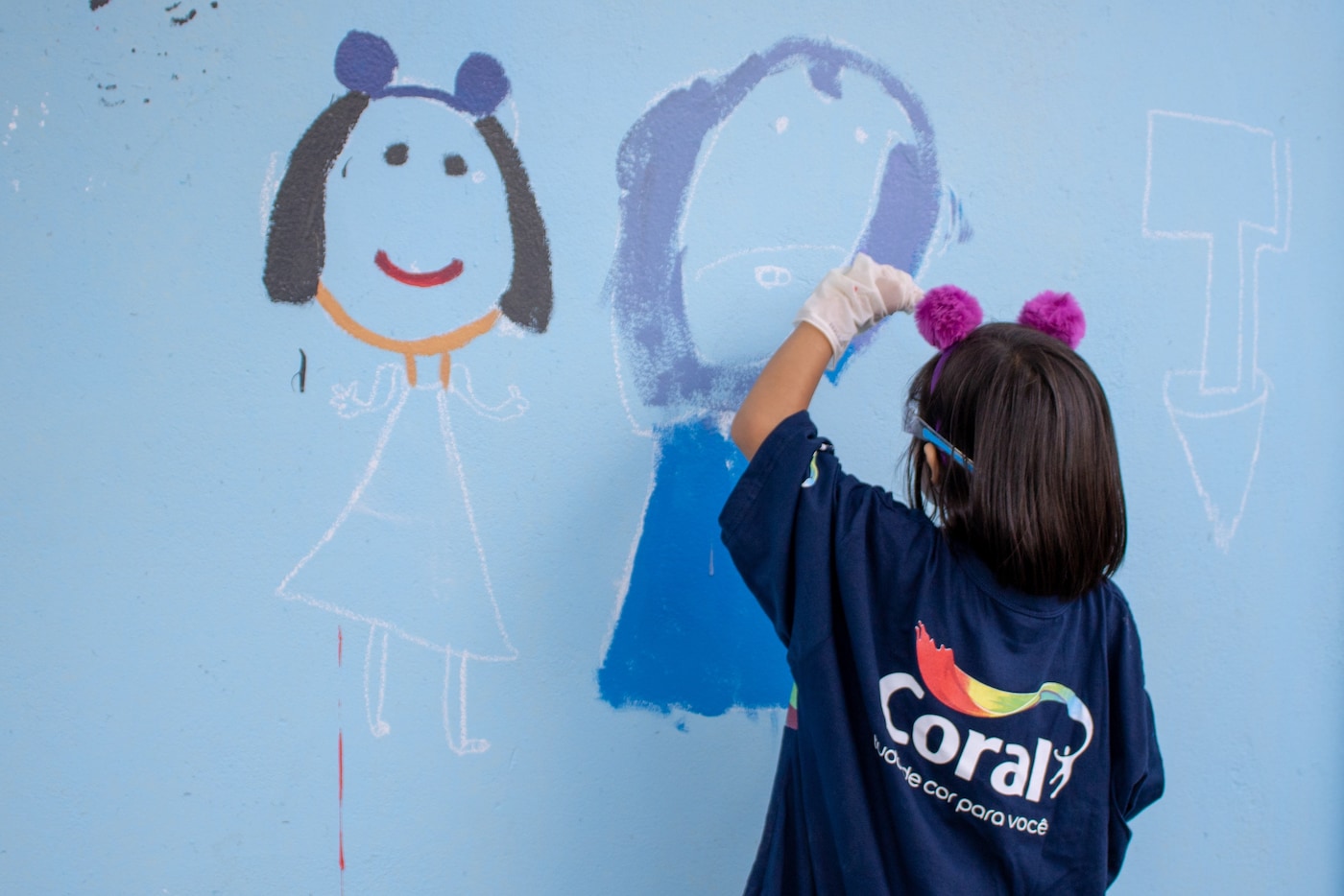 Criança pintando um muro com a Experiência lúdica na Parceira da ImaginaC e Movimento Tudo de Cor da Coral.