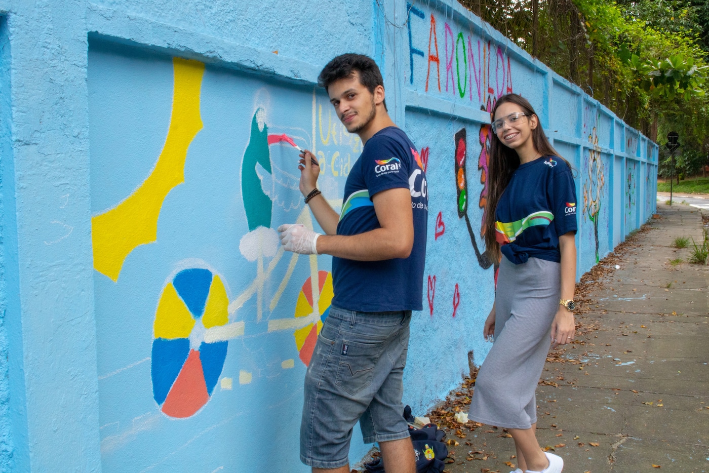 Homem e mulher pintando um muro em Parceira da ImaginaC e Movimento Tudo de Cor da Coral.