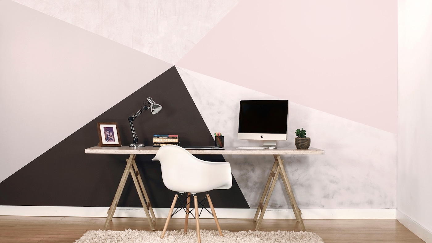 Home office com parede decorada com efeito geométrico.