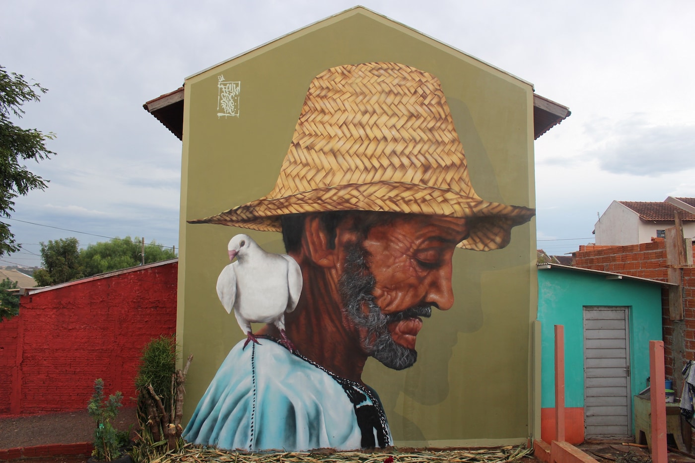 Casa pintada com rosto de um homem de chapéu e uma pomba no ombro projeto Bezalel.