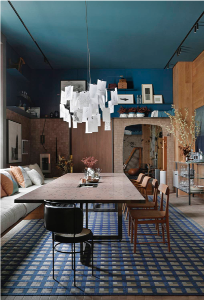 Sala de jantar com mesa ao centro e parede com tons de azul.