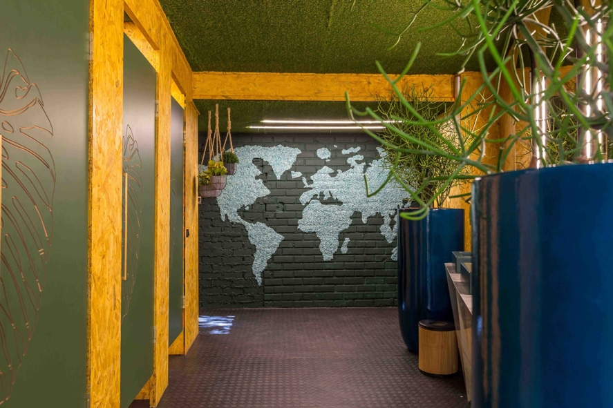 Ambiente externo decorado com parede mapa mundi com tons de verde.